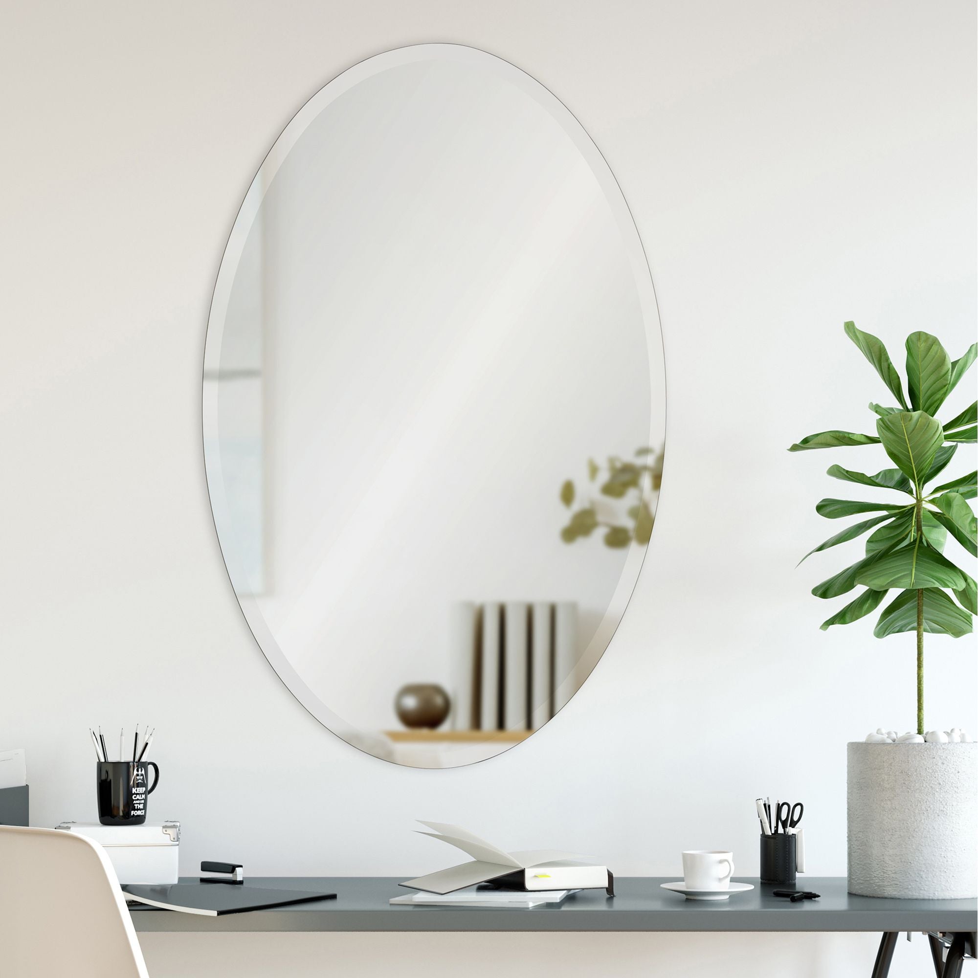 Yen mirror by Renwil, oval shape mounted on a wall above a modern desk with plants.