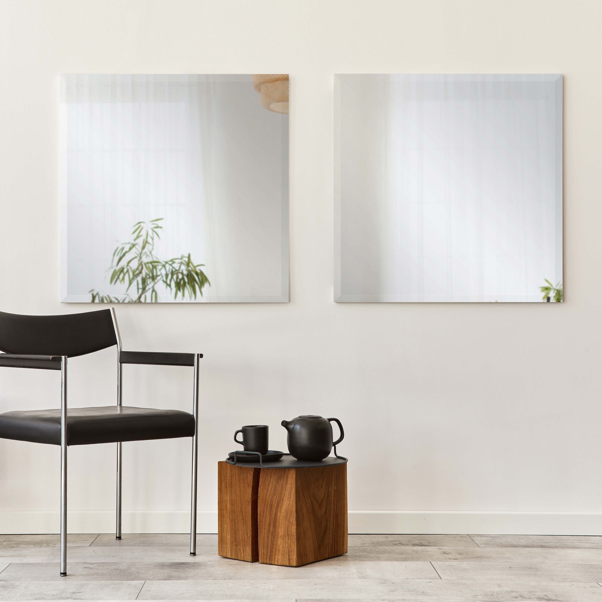 Vogue mirrors mounted on a wall beside a black chair and wooden table, enhancing a modern interior.