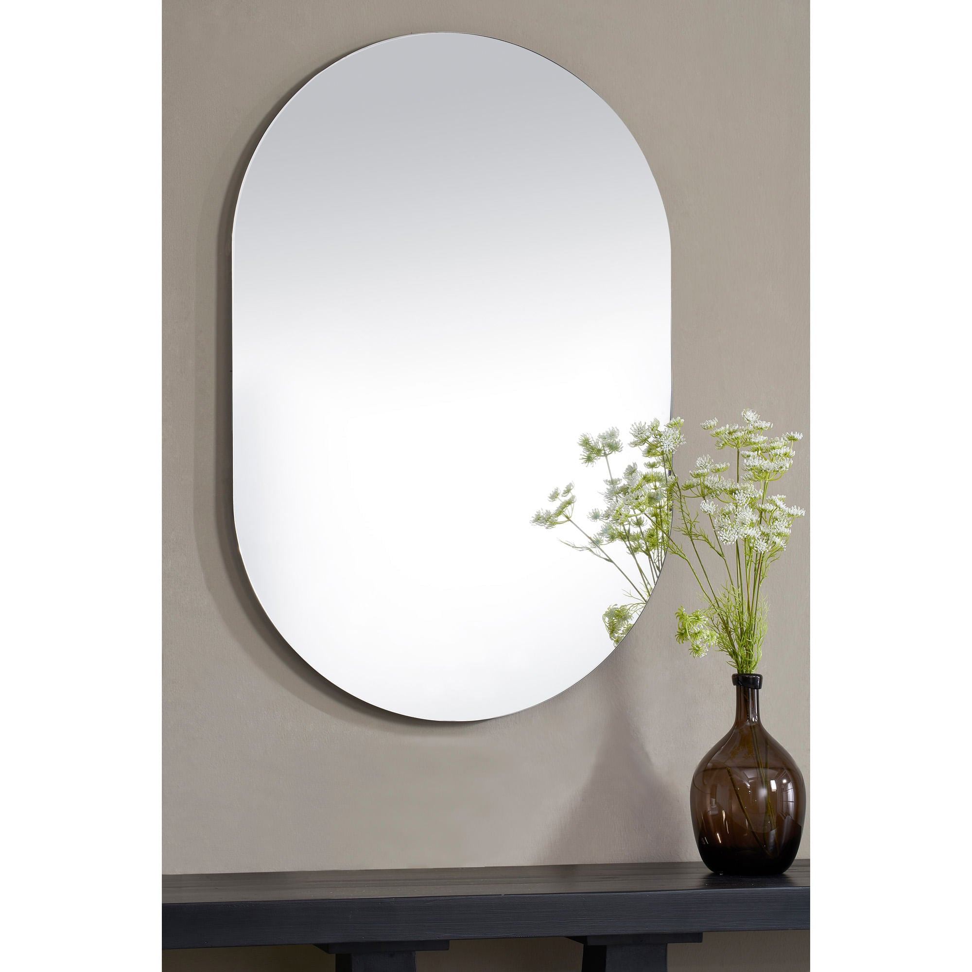 Salta mirror by Renwil displayed on a wall with a vase of flowers beside it.