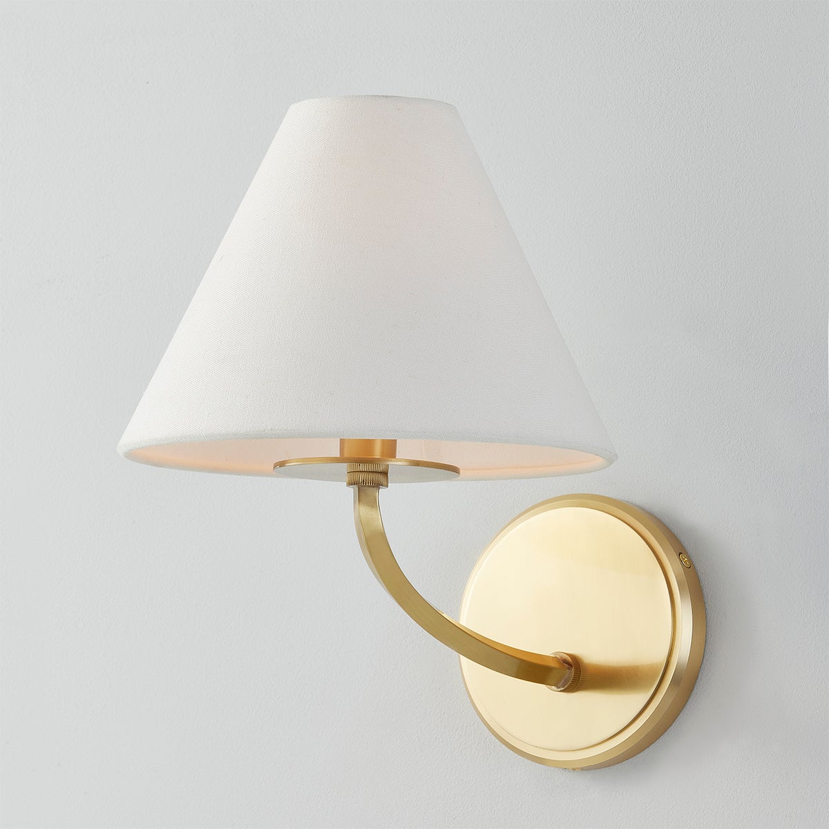 Close-up of the Stacey Wall Sconce in aged brass showing the arm curve and shade silhouette.