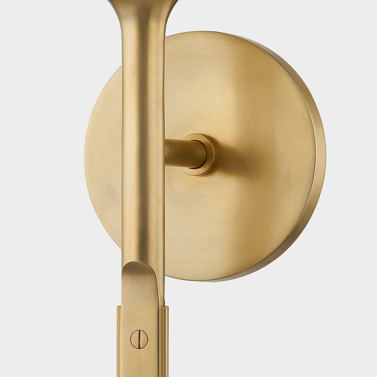 Close-up of the Brewster Wall Sconce in aged brass showing the arm curve and shade silhouette.