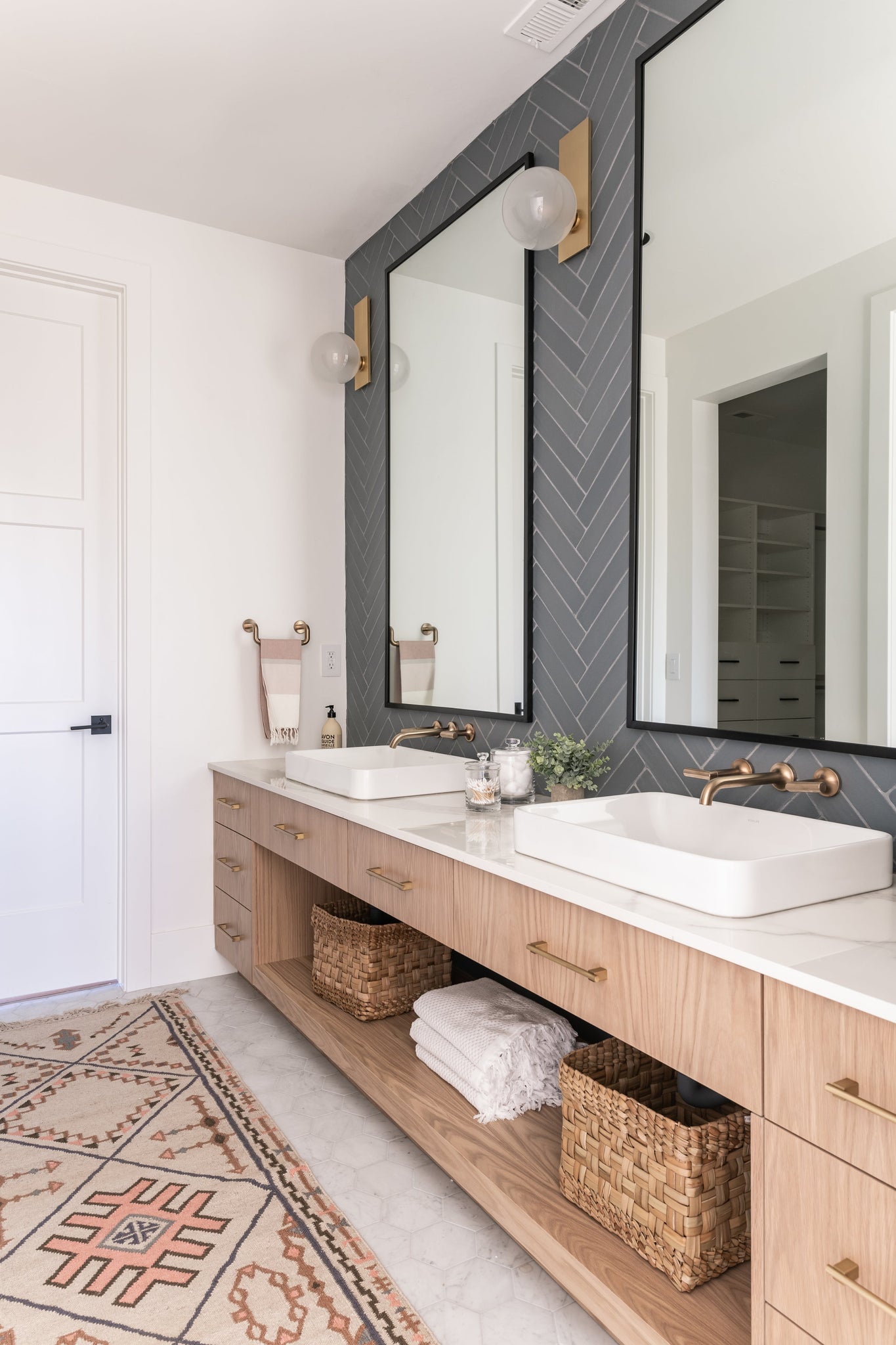 Hinsdale Wall Sconce in aged brass styled in a modern bathroom for warm, layered light at Laurie Yapp Home.