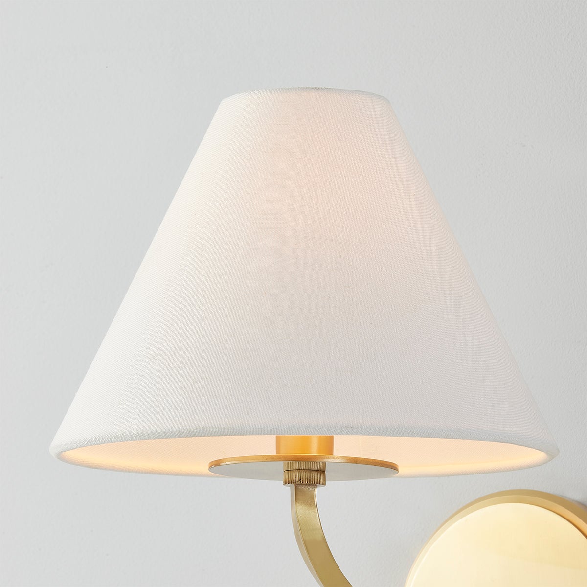 Stacey Wall Sconce in aged brass shown from a second angle to highlight the arm curve and shade silhouette.
