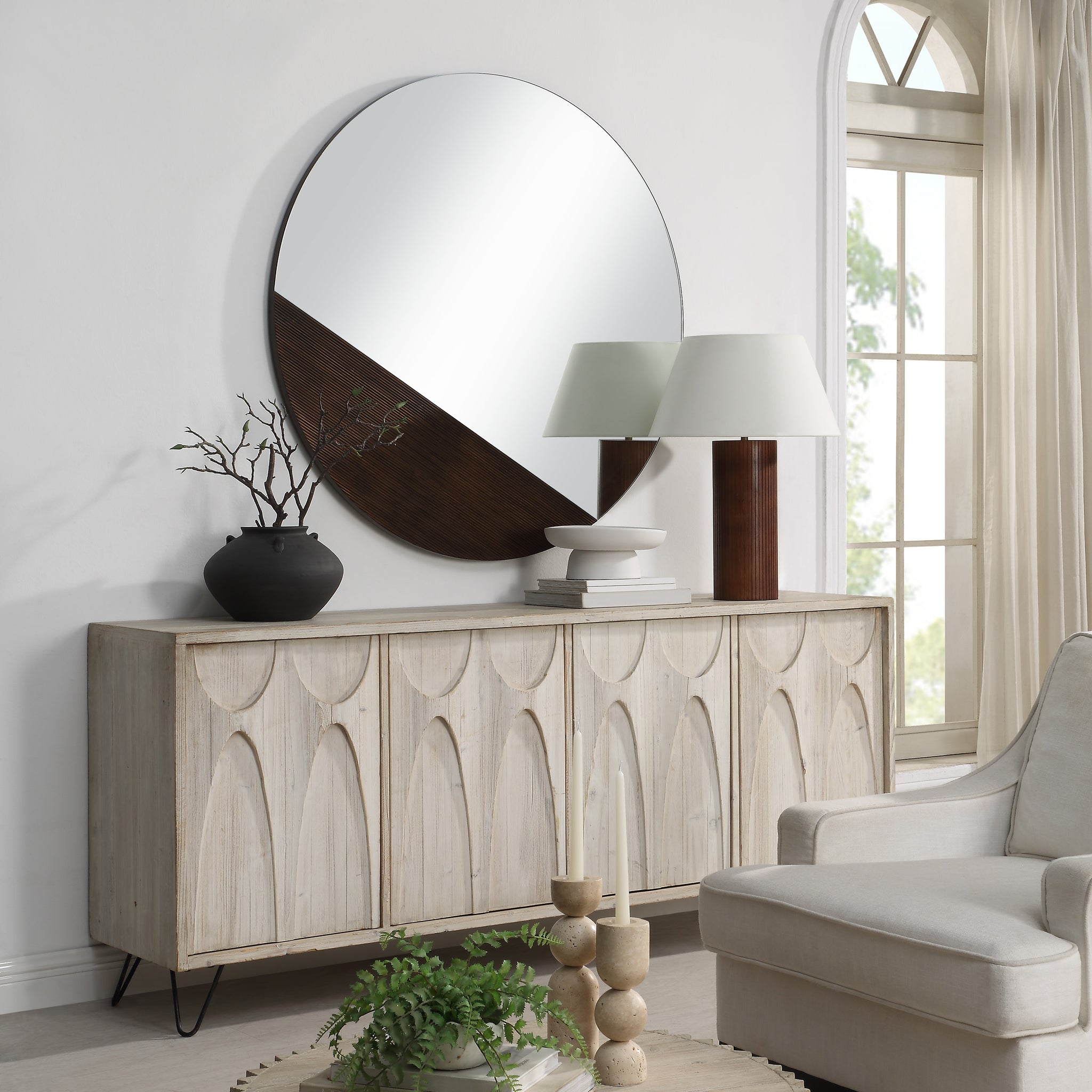 Ronda mirror hung above a wooden sideboard in a bright living room setting.