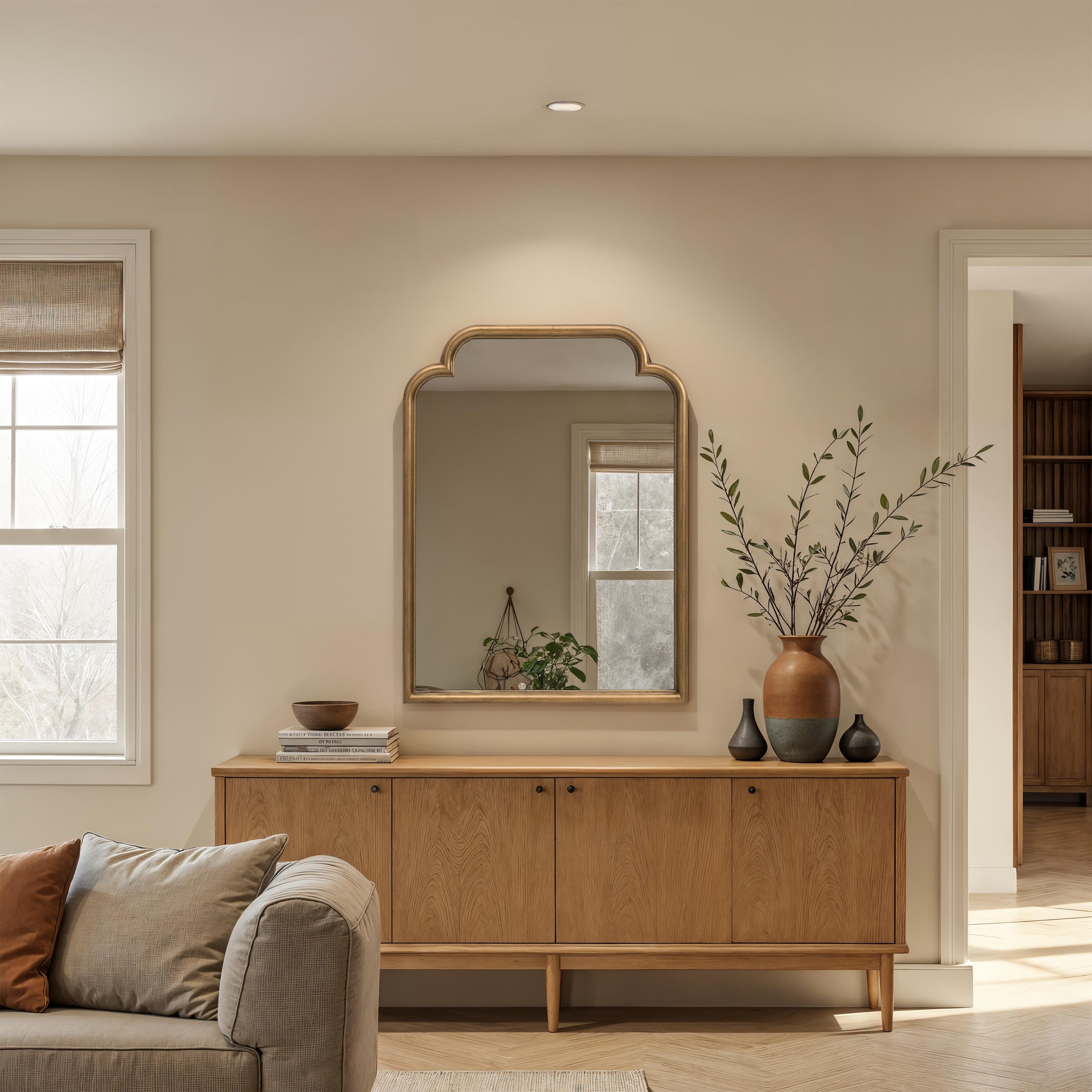Emilien mirror with a gold frame, displayed above a wooden sideboard in a cozy living room setting.