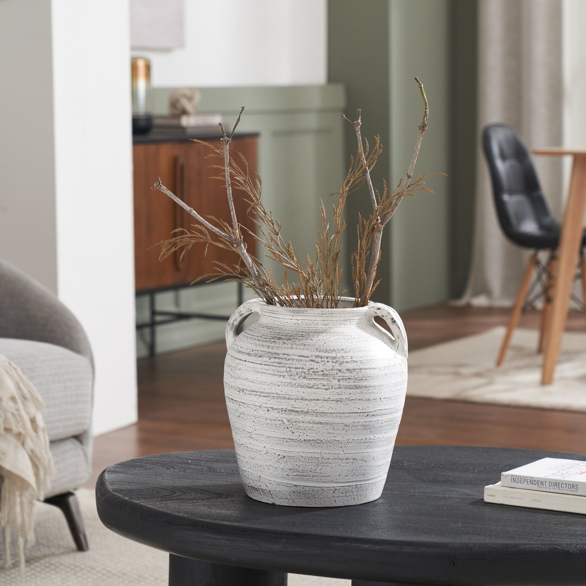 Blanco vase by Renwil on a black table, filled with dried branches in a modern living room