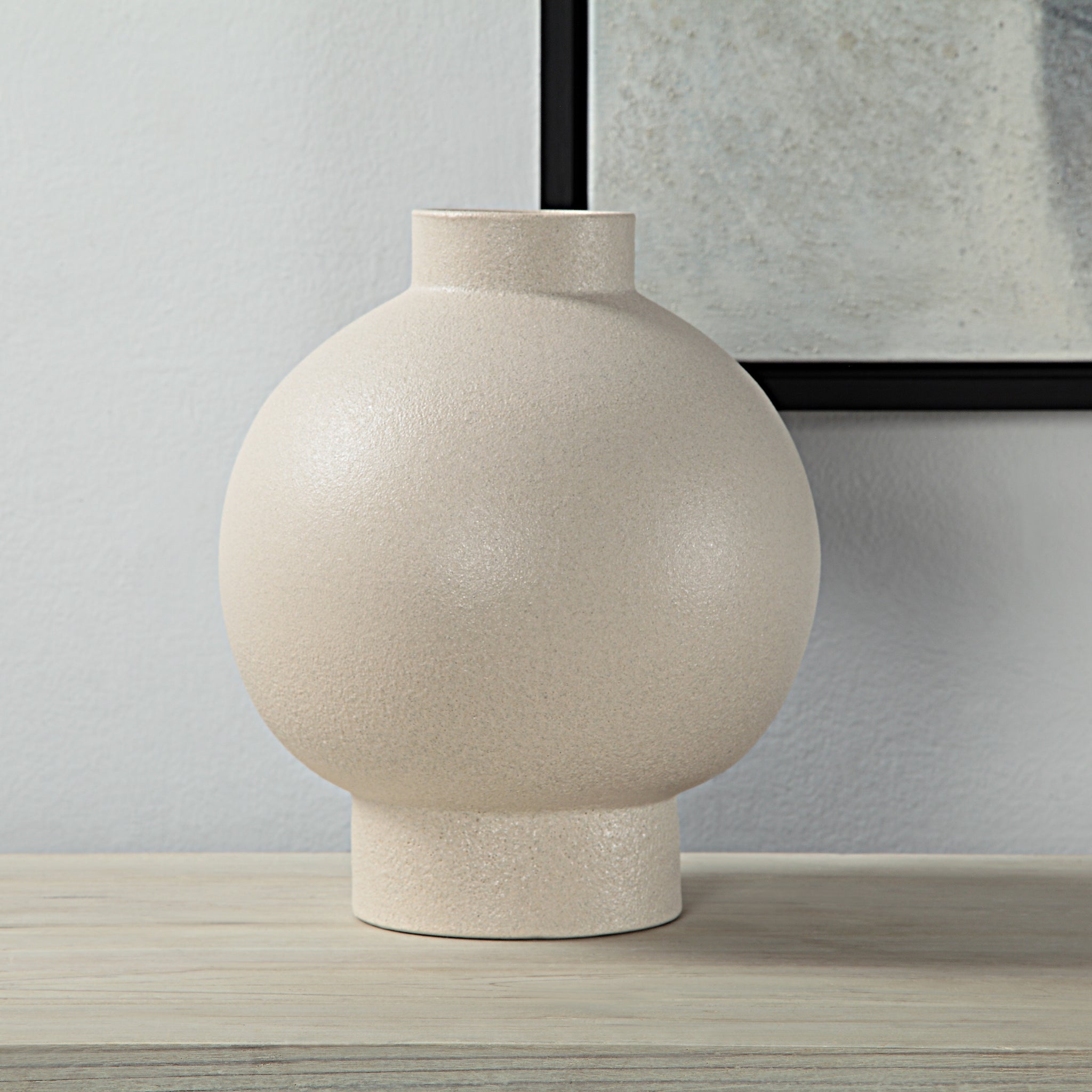 Lamoureux Vase by Renwil, beige ceramic vase displayed on a wooden surface against a wall.