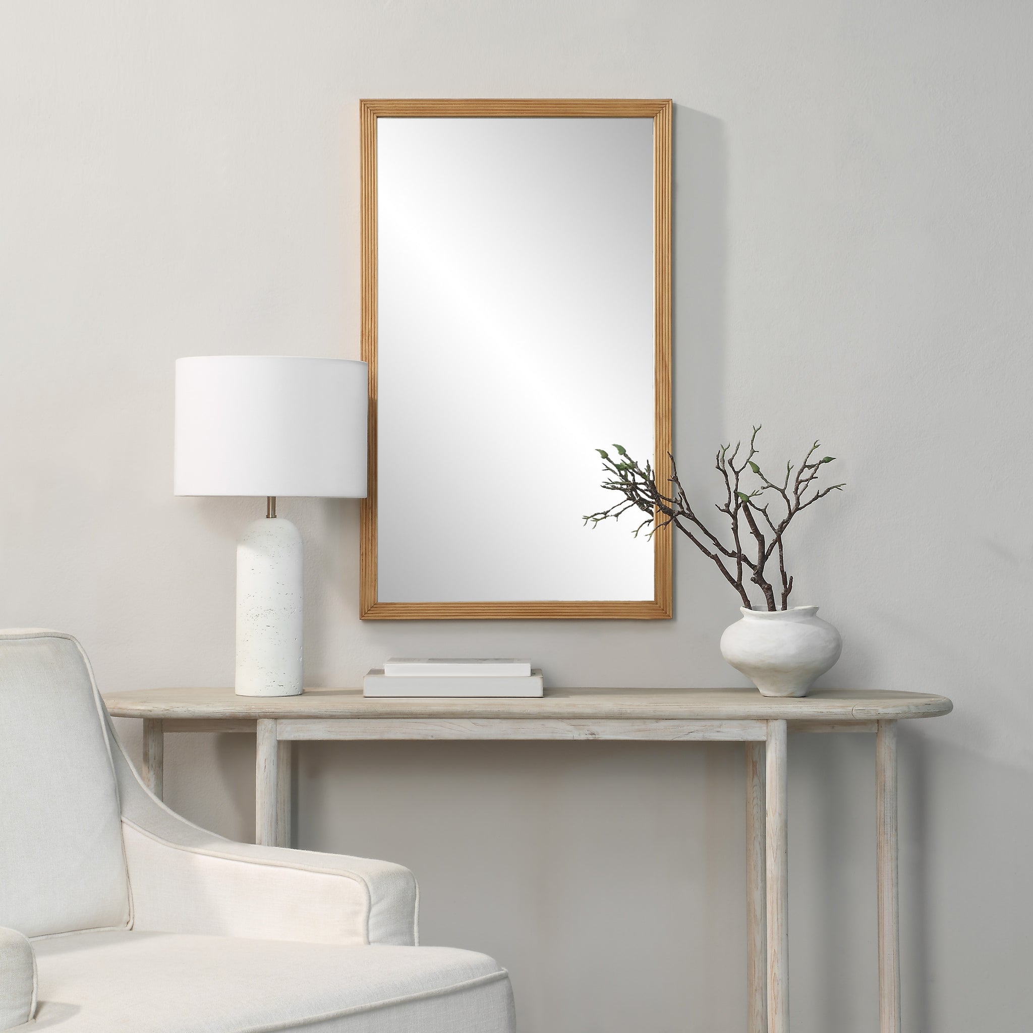 Salia mirror by Renwil displayed in a room setting, paired with a lamp and decorative vase.