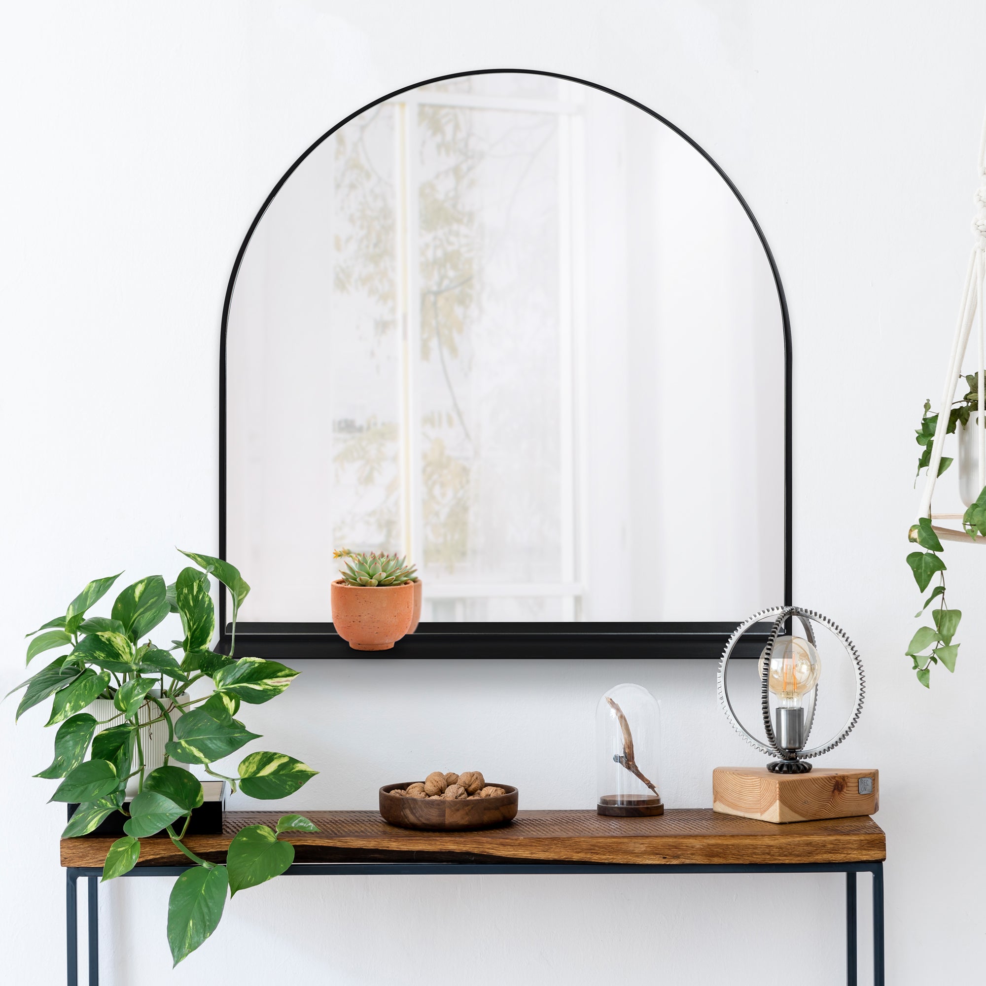 Wearstley Wall Mirror displayed above a wooden console table with plants and decorative items.