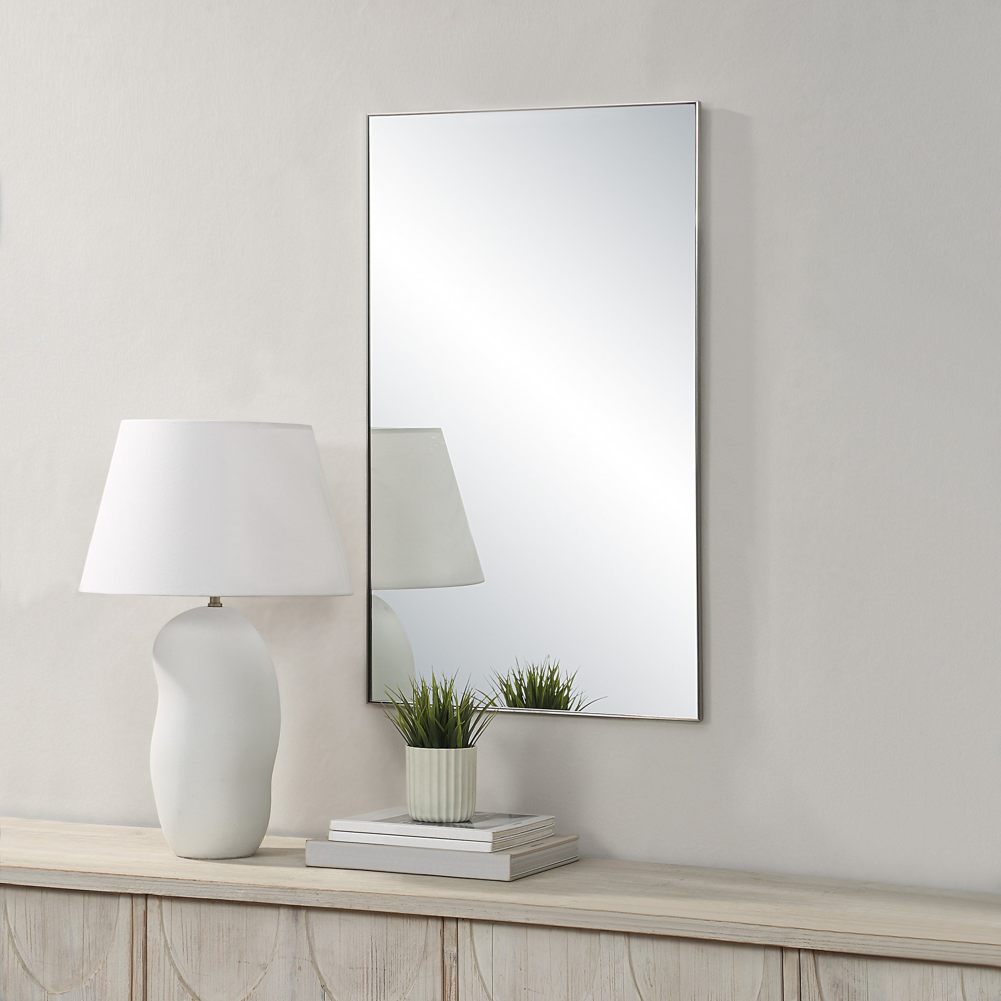 Spili mirror by Renwil displayed on a wall beside a lamp and plant, showcasing its decor style