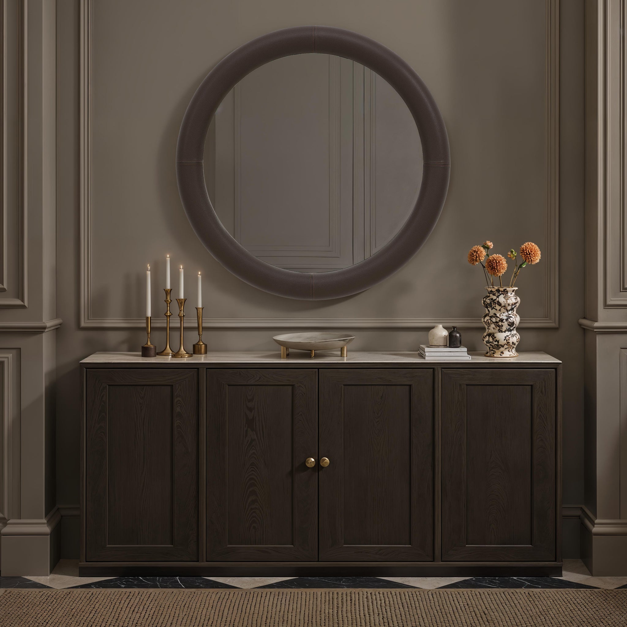 Potro mirror displayed above a dark wooden cabinet with candles and flowers.