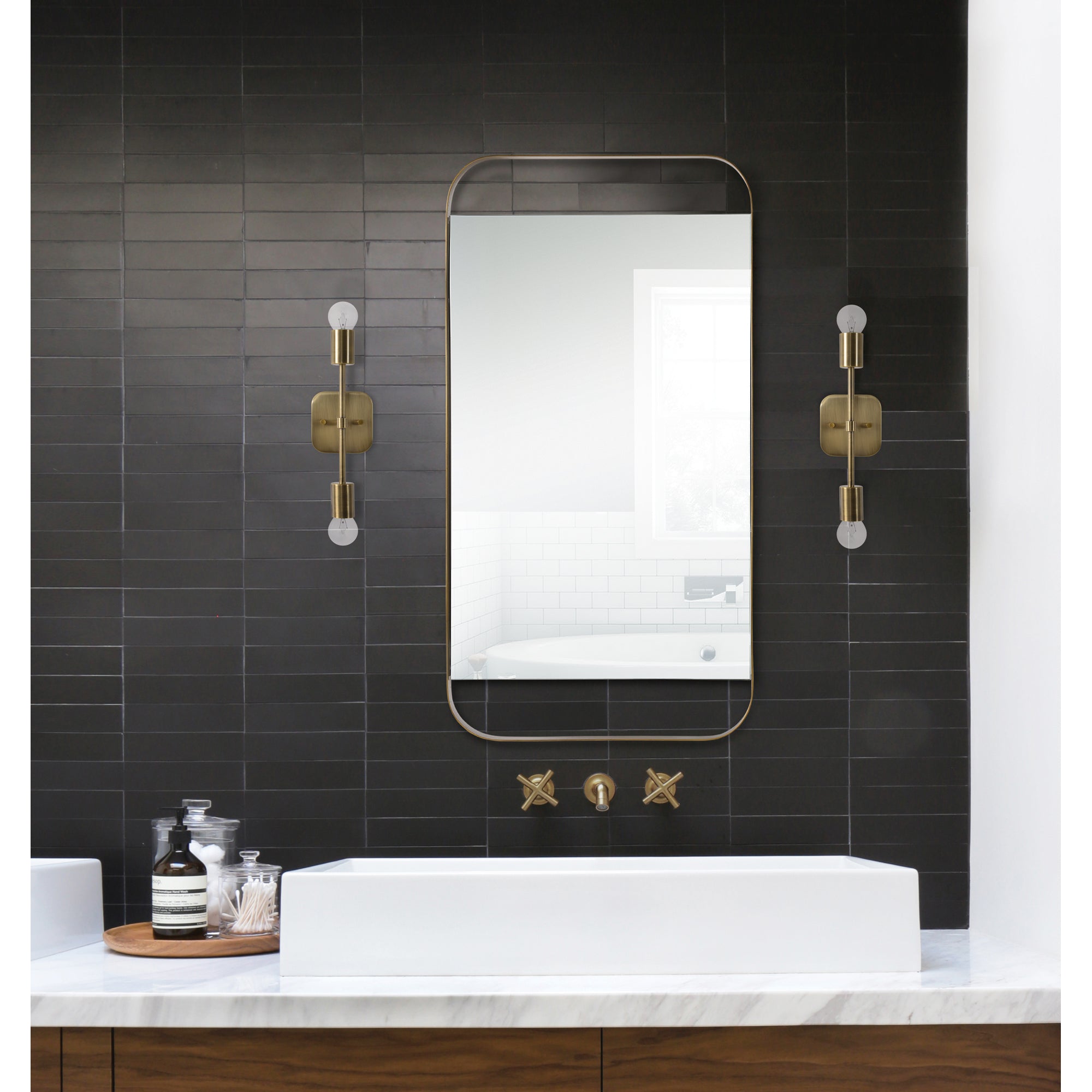 Anka Wall Sconce by Renwil in a bathroom setting, flanking a mirror on a dark tiled wall.