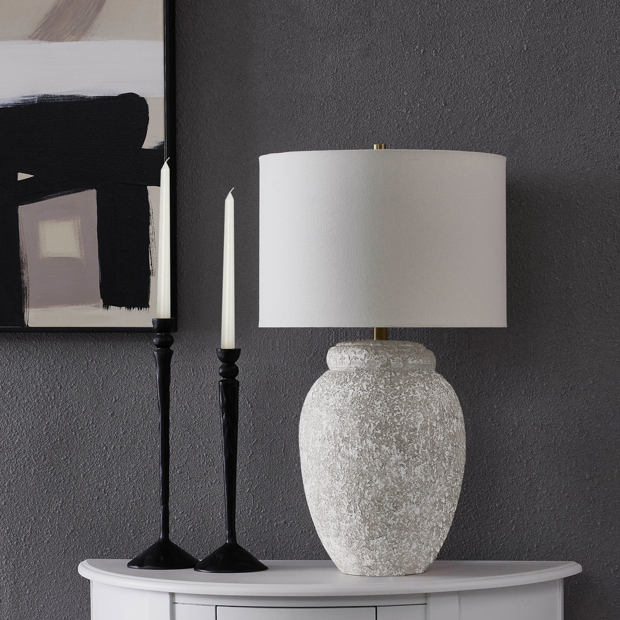 Wassily Table Lamp on a table with black candlesticks and abstract wall art in the background.