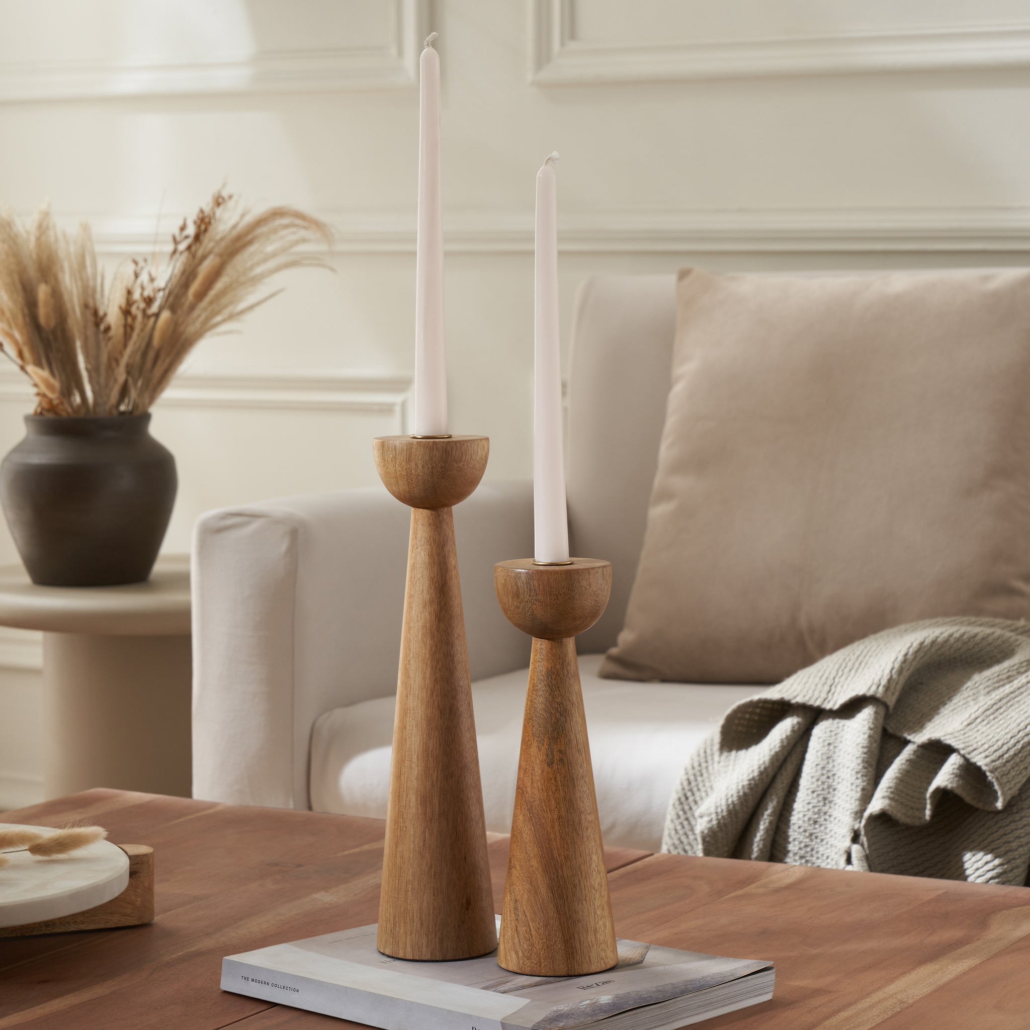 Laurier candle holder set in natural wood finish with two tapered holders and white candles on a wooden table
