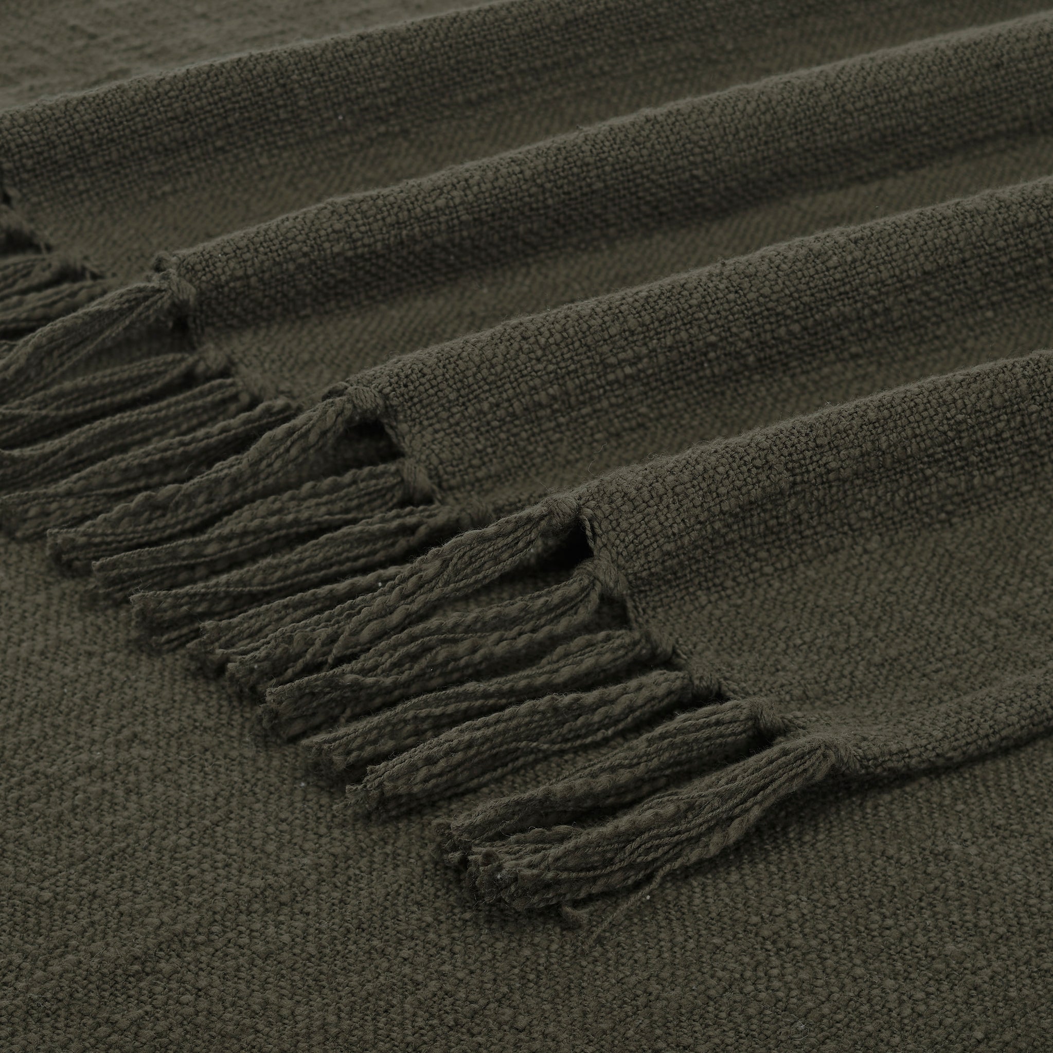 Fringe detail of Chalamet Throw Blanket in dark green, emphasizing woven edges.