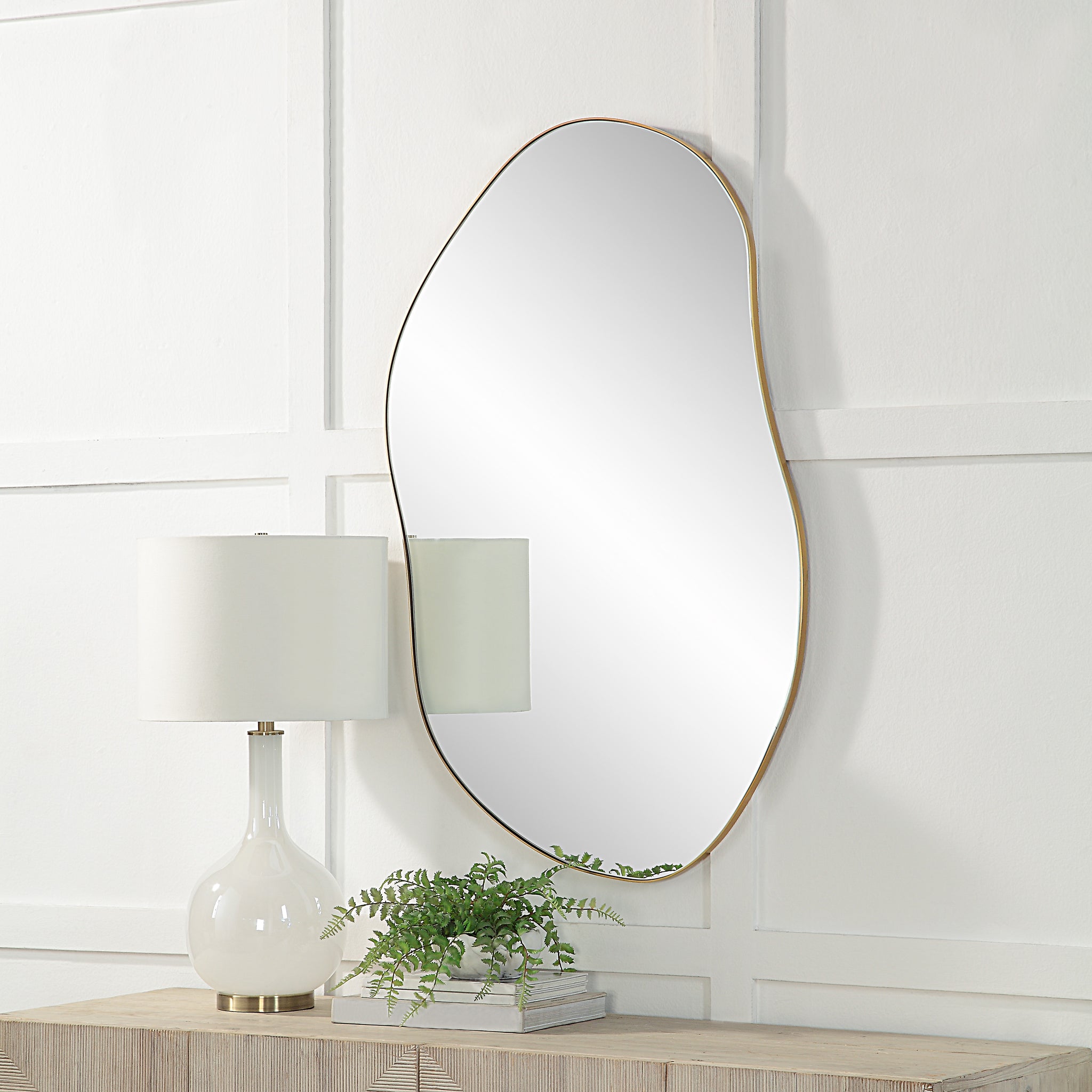 Noria Wall Mirror mounted above a table with a lamp and plant