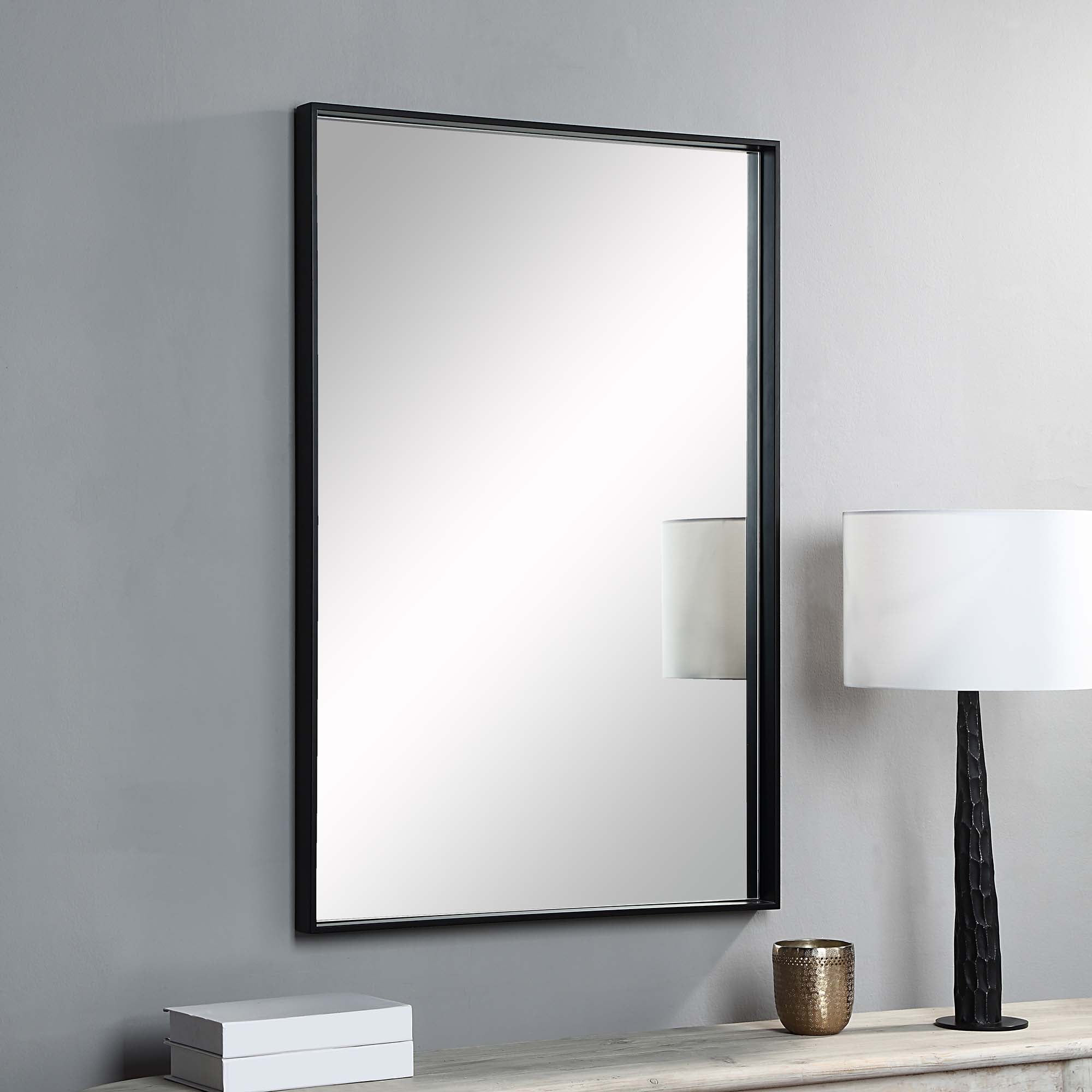 Annalise Wall Mirror mounted on a wall next to a lamp, featuring a modern black frame.