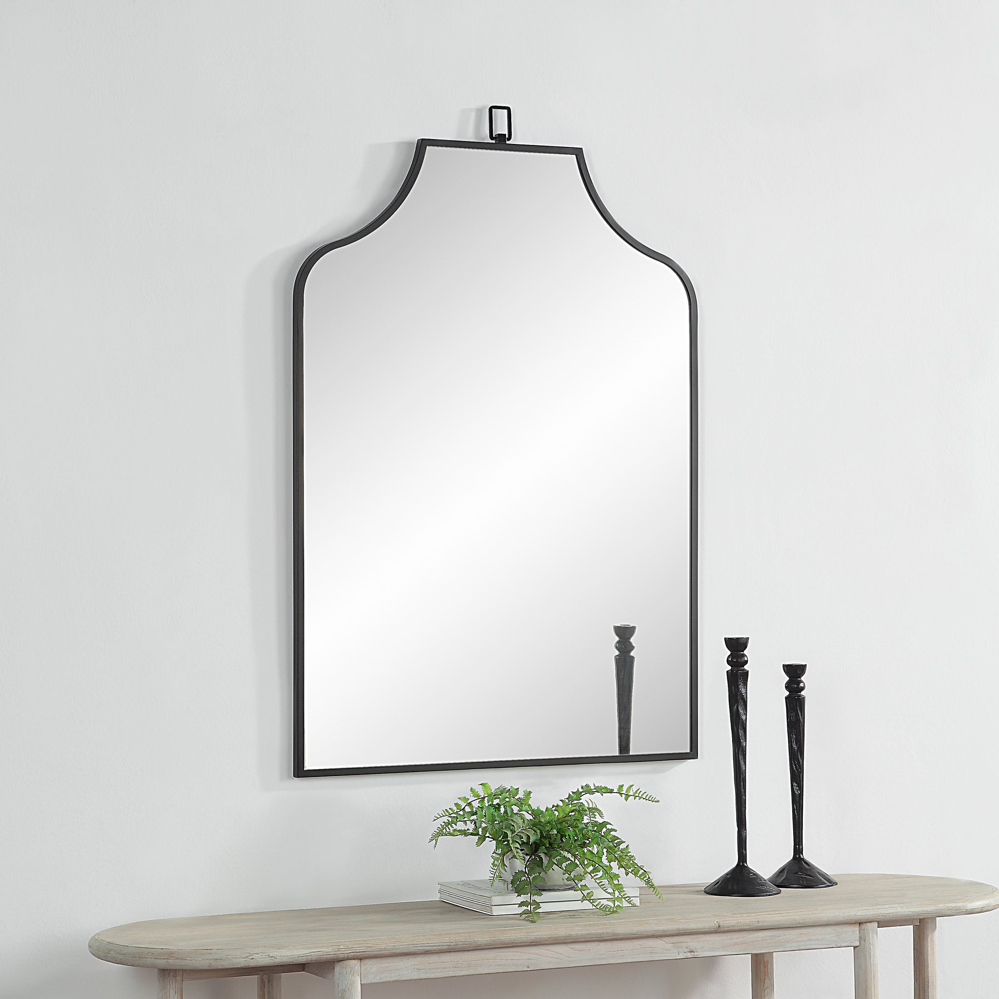 Breda Wall Mirror displayed above a wooden table with candles and a plant.