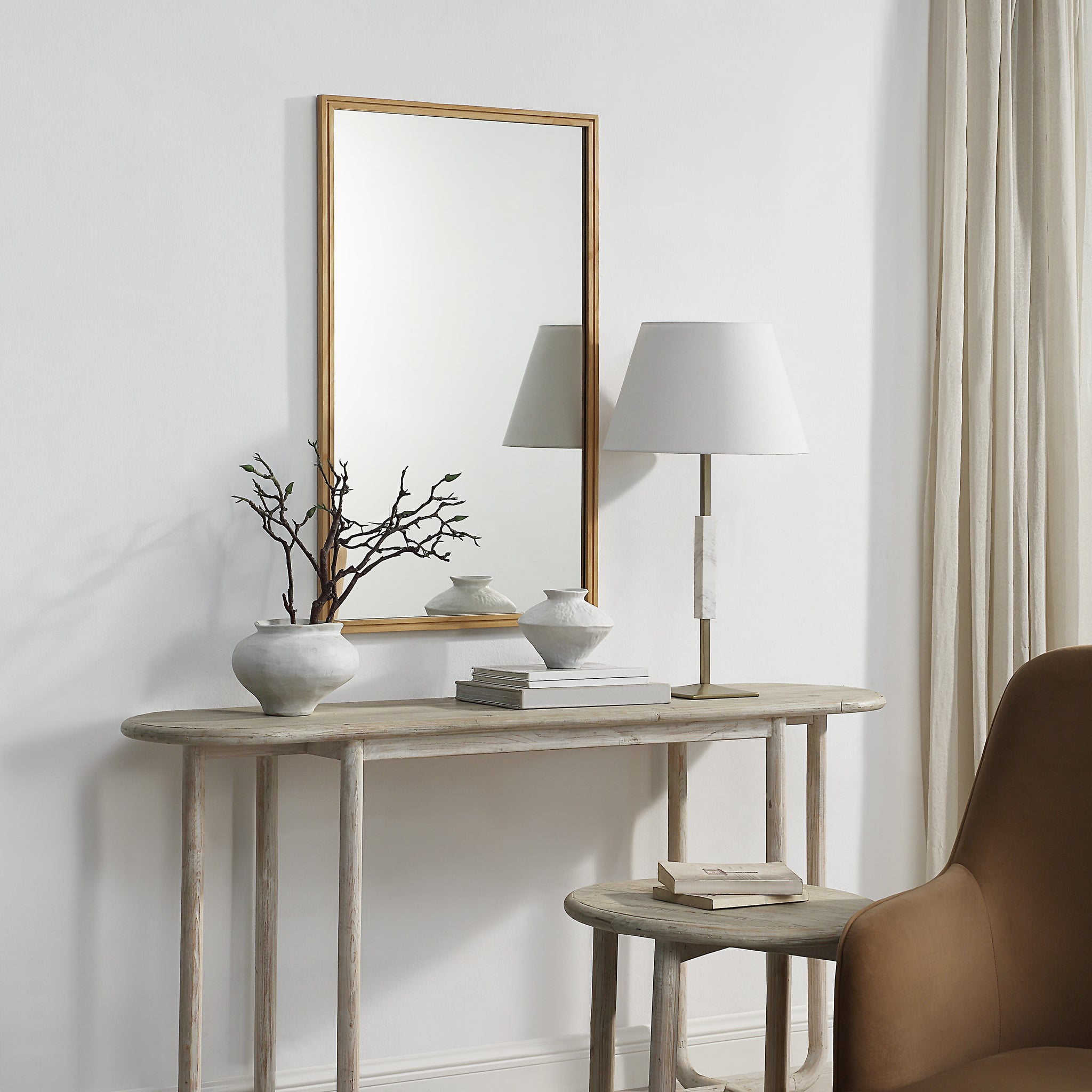 Canas mirror displayed above a console table with decorative items and a lamp.