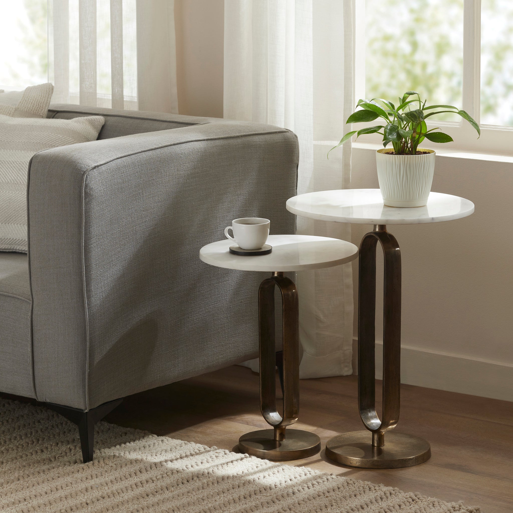 Irene Side Tables styled beside a gray sofa, with a coffee cup and plant on the tops.