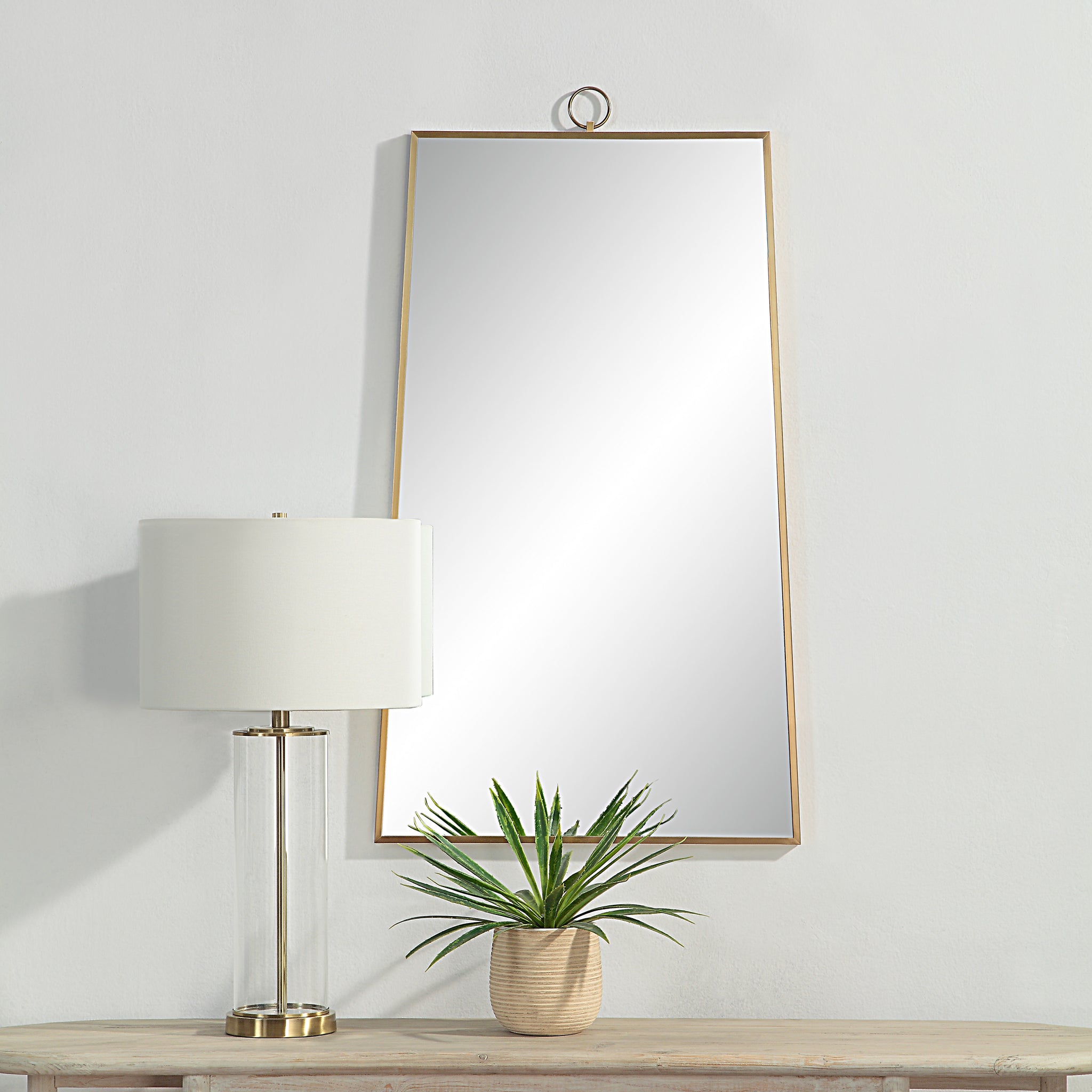 Ariadne Wall Mirror displayed in a room with a lamp and plant on a table.