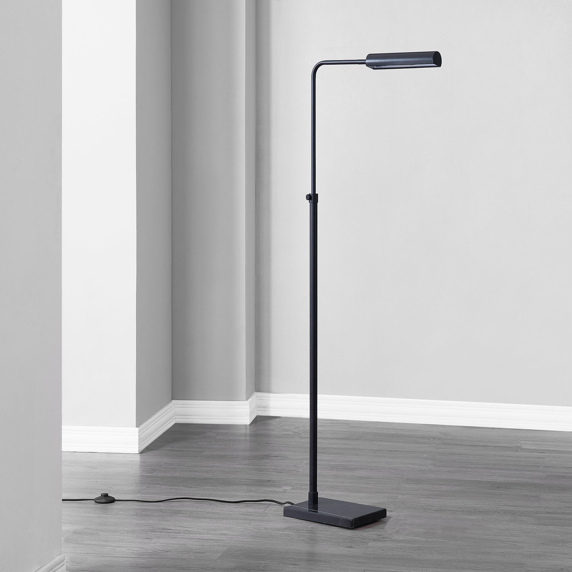 Fadia Floor Lamp positioned in a room corner, with a black finish and visible power cord.