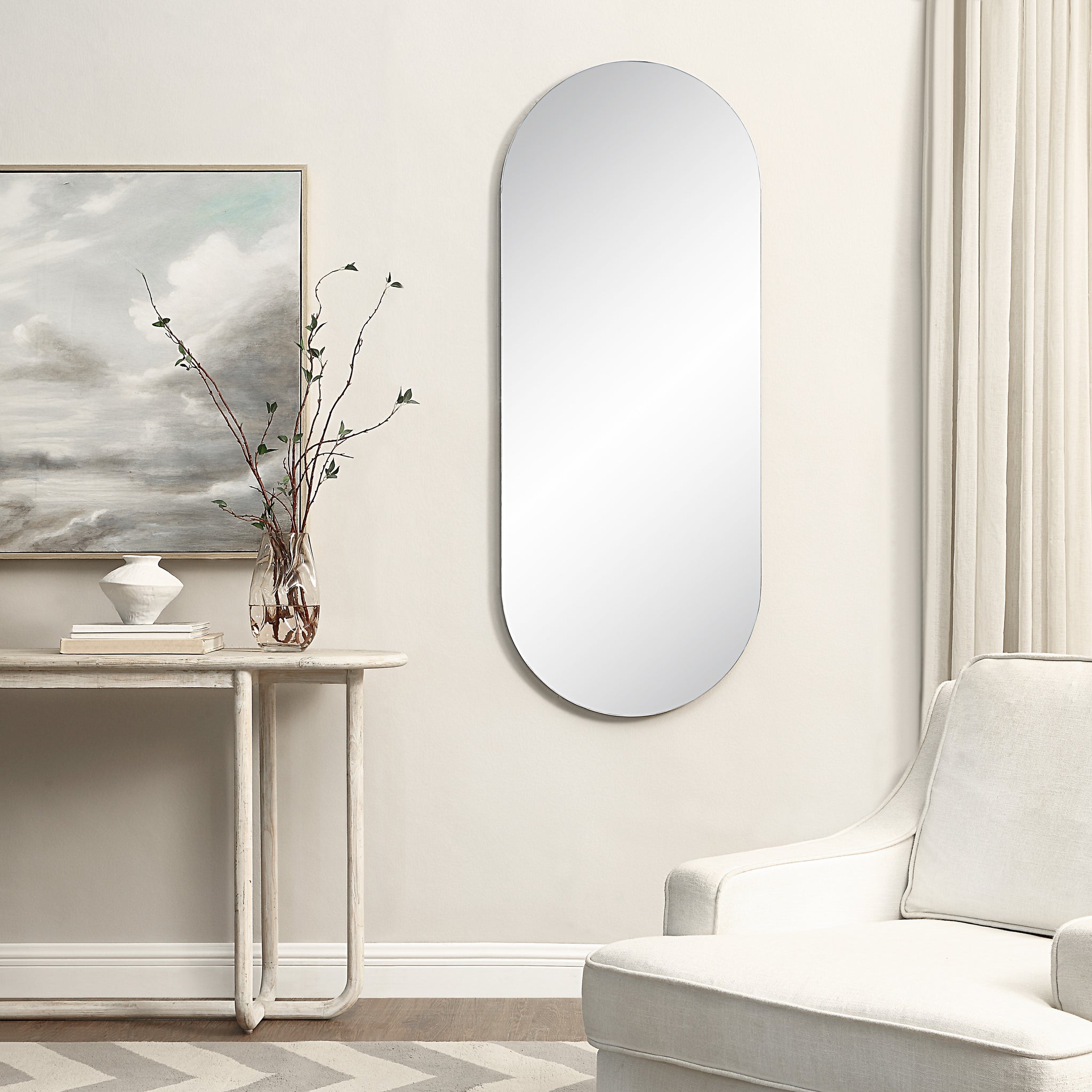 Kastelli mirror mounted on a wall beside a decorative table and artwork.