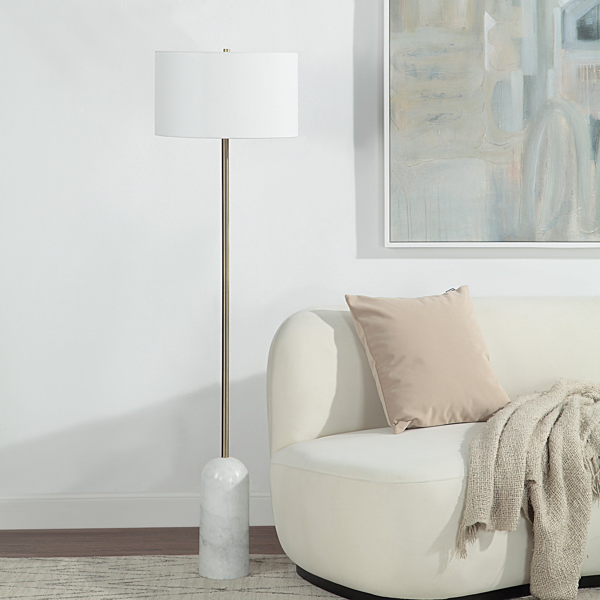 Lozica Floor Lamp beside a cream sofa, featuring a white shade and marble base.