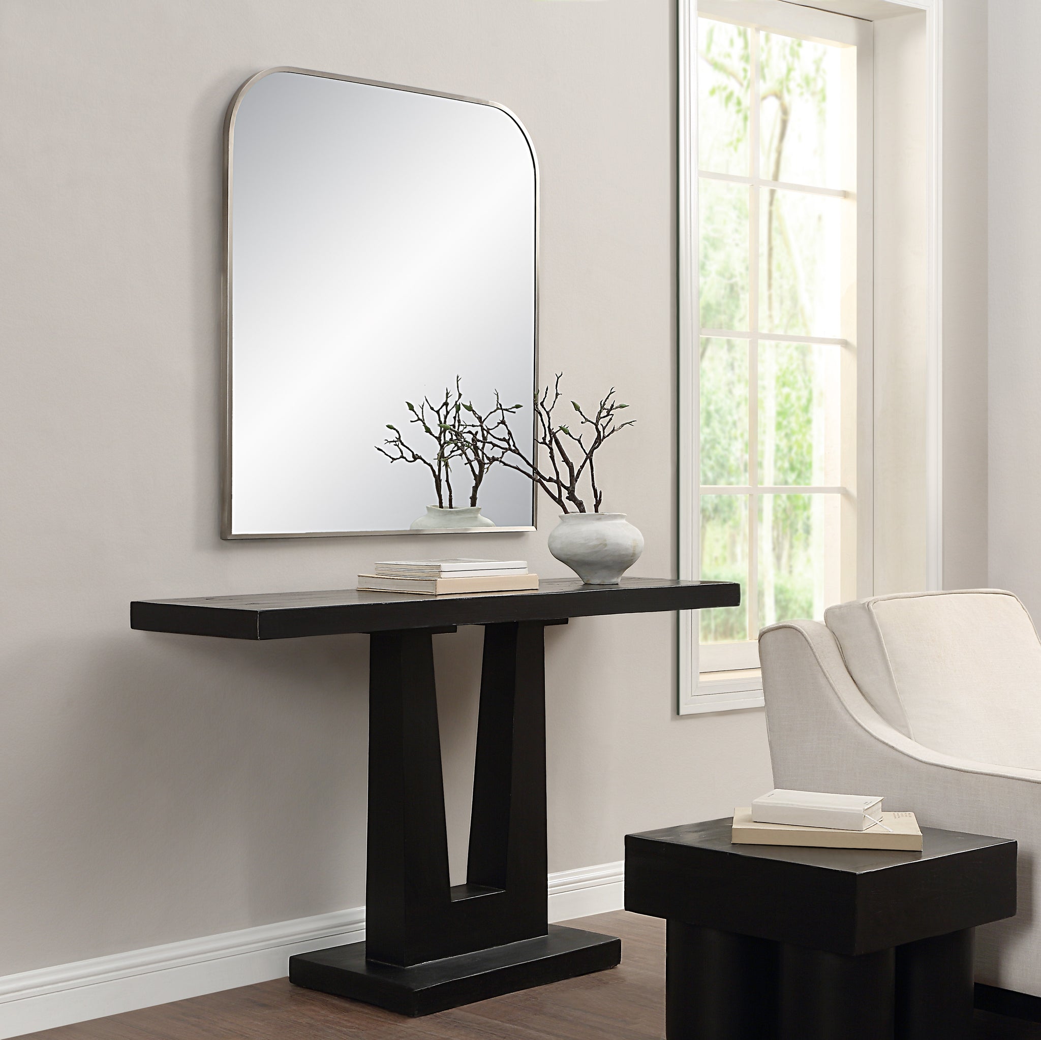 Salma mirror displayed above a black console table in a modern living room setting