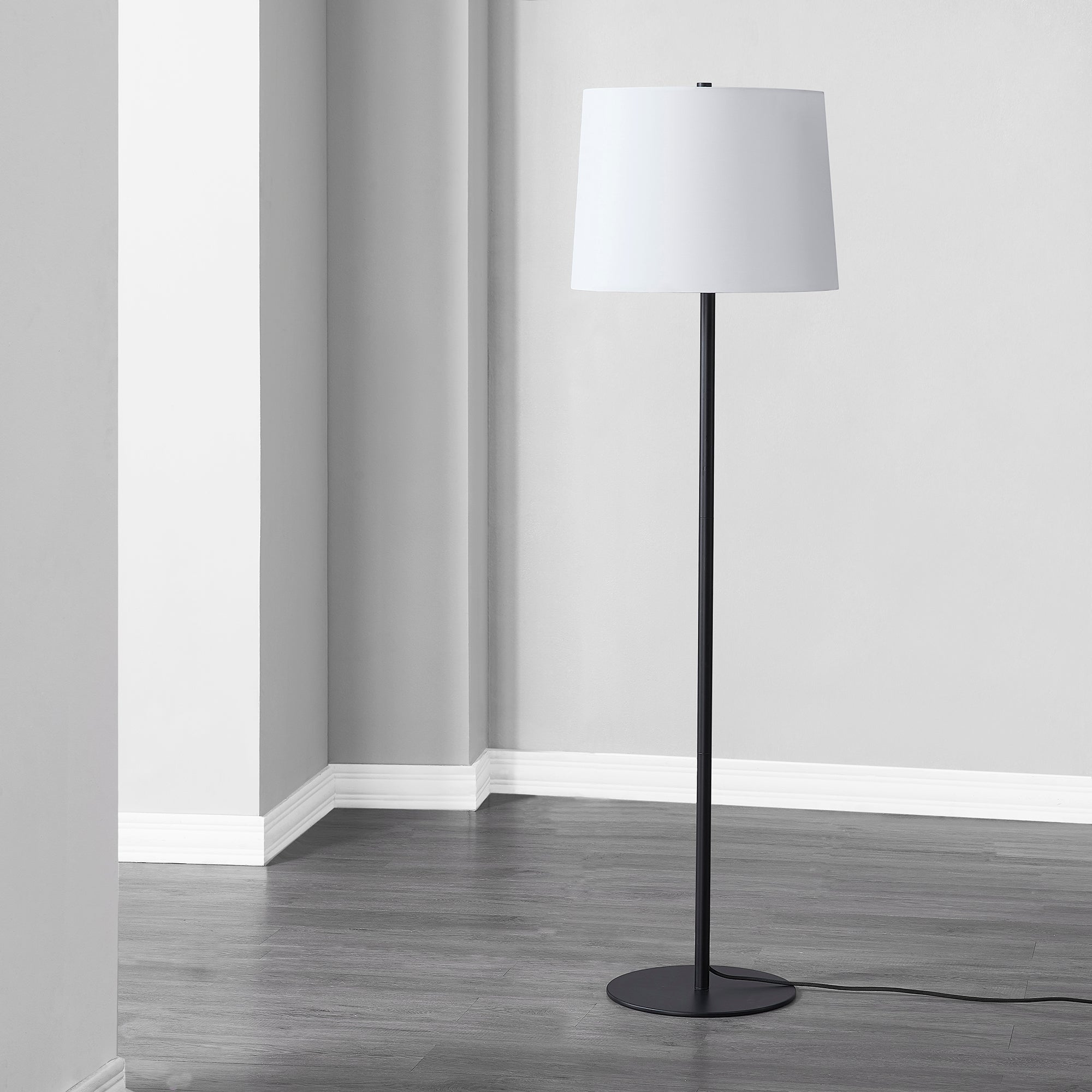 Nevin Floor Lamp in a modern interior, showcasing its black base and white shade.