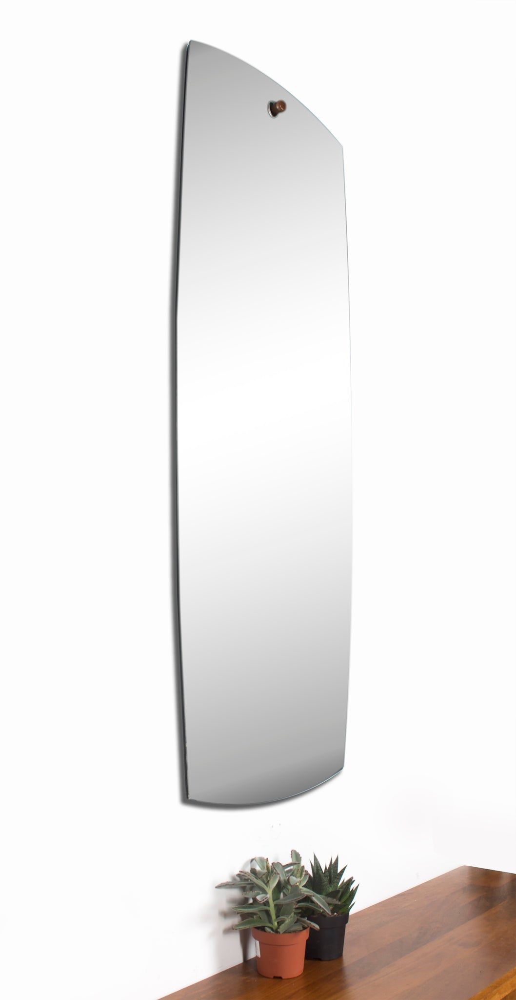 Corbel Wall Mirror displayed vertically, featuring a curved edge and mounted above potted plants.
