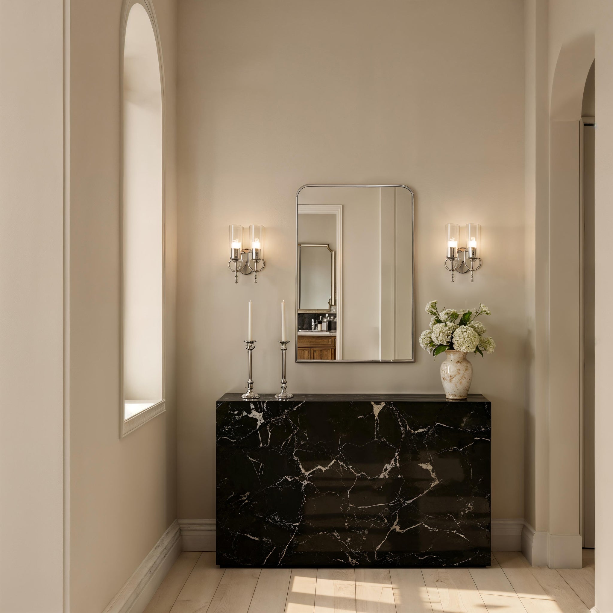 Jackline mirror by Renwil displayed in a stylish interior, above a black marble console with candles and flowers.