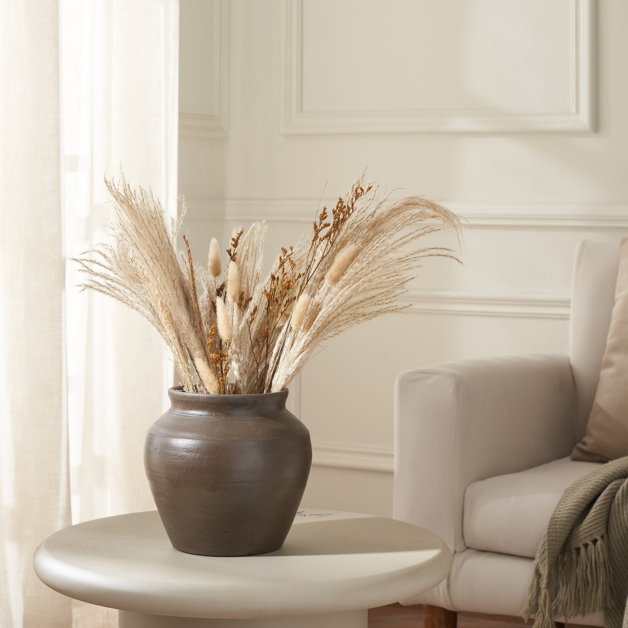 Bondi vase filled with dried pampas grass, placed on a table in a bright living room.
