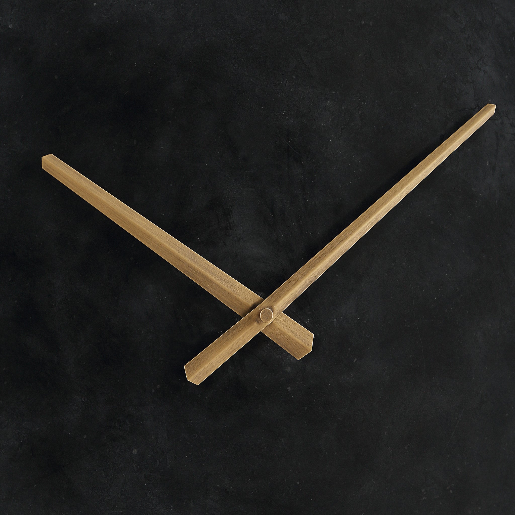 Close-up of Darnay Wall Clock's gold hands against a black background.