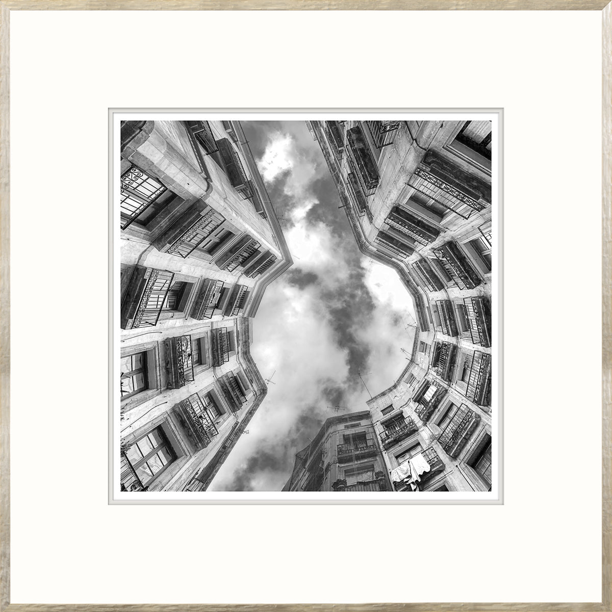 Upward Focus wall art featuring a black and white view of buildings and clouds from below.