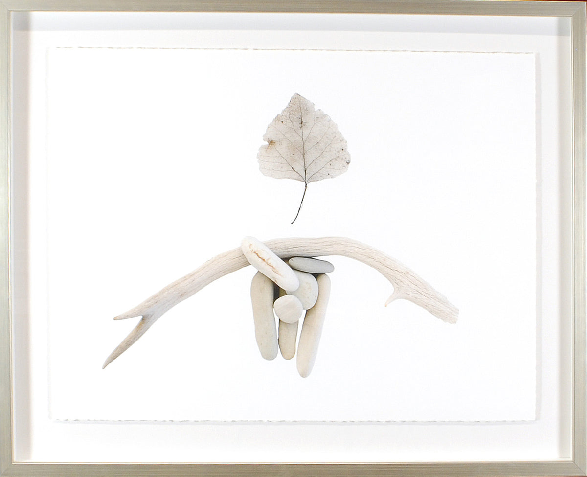 Found Objects wall art featuring smooth stones and driftwood with a leaf on a white background