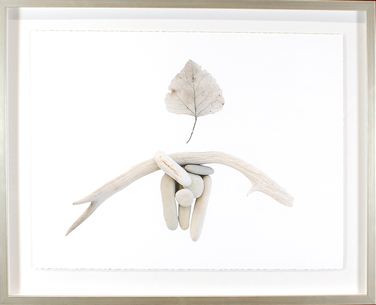 Found Objects wall art featuring smooth stones and driftwood with a leaf on a white background