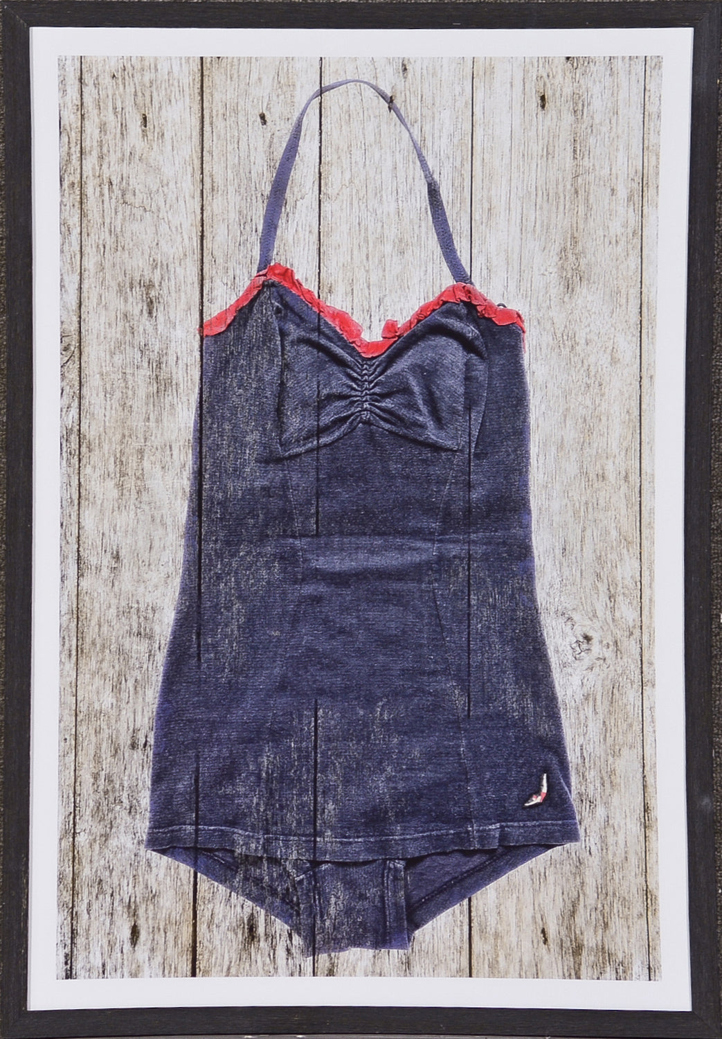 Vintage Swimsuit wall art featuring a navy swimsuit with red ruffle trim on a wooden background.