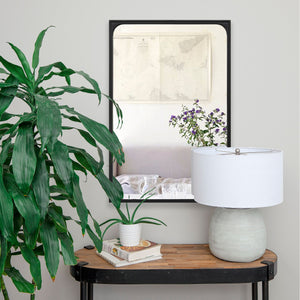 Sorella mirror by Renwil displayed in a room with plants and a lamp, adding elegance to the decor.