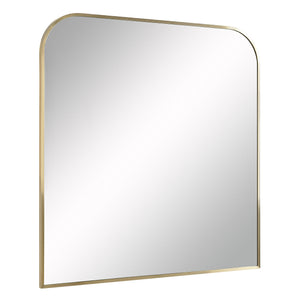 Joan mirror with a rounded top and antique brushed brass frame, reflecting light.