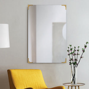 Eros mirror mounted on a wall beside a yellow chair and floral decor.