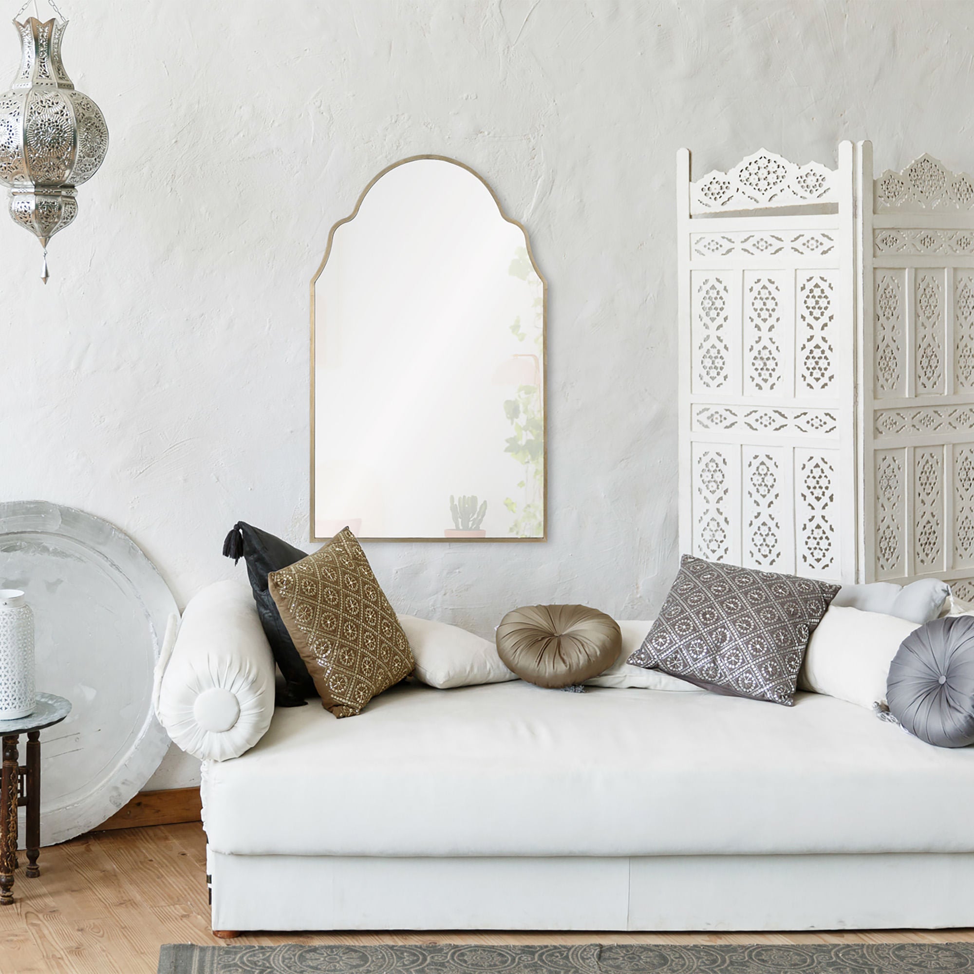 Natasha mirror with an arched top, framed in light wood, reflecting a cozy living space with decorative pillows.