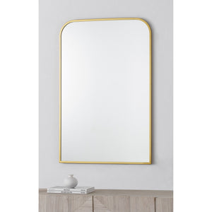 Merrimack mirror with a sleek gold frame, featuring a rounded top and a clear reflective surface, displayed against a light wall.