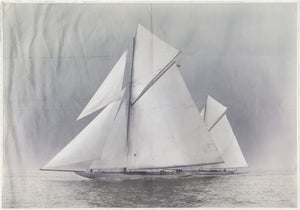 Indigo Stained – Yachts Constitution & Columbia, featuring a vintage sailboat with large white sails on calm waters.