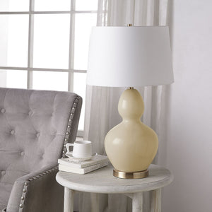 Jesula Table Lamp Set - cream ceramic base with white shade, placed on a side table next to a gray chair
