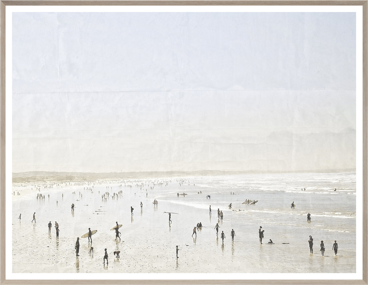 Idyllic Surf wall art depicting a lively beach scene with surfers and people, framed in light wood.