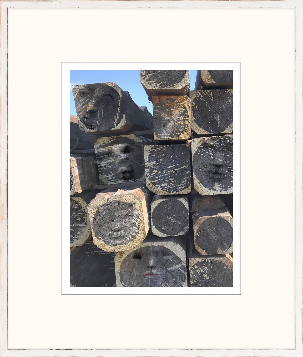 The Hidden Series V wall art featuring stacked logs with abstract faces, framed in white.