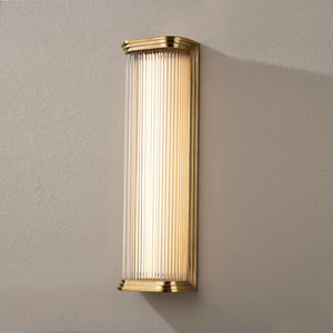 Newburgh Bath And Vanity 5.25" x 17" in aged brass shown from the front to reveal the arm spread and shade silhouette.