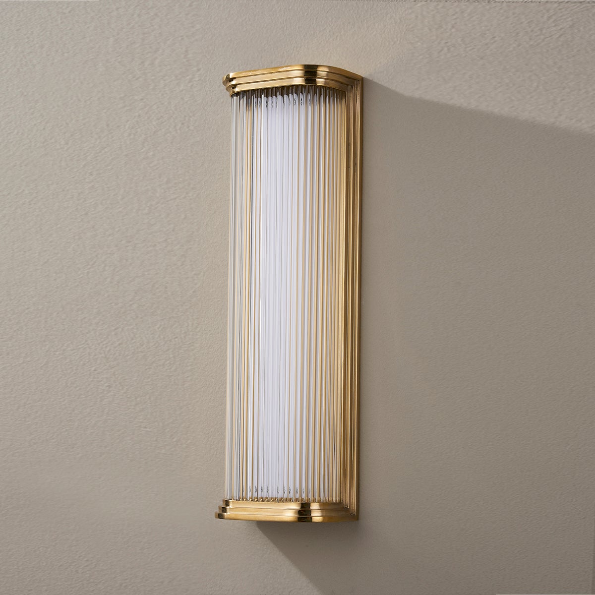 Close-up of the Newburgh Bath And Vanity 5.25" x 17" in aged brass showing the arm spread and shade silhouette.