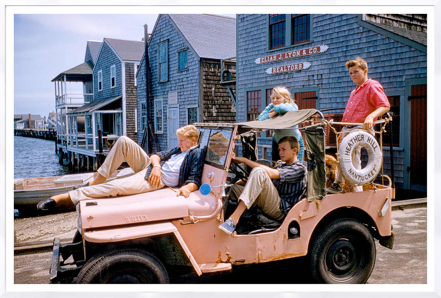 Toni Frissell Nantucket C. 1957 wall art featuring children in a pink jeep near coastal buildings.